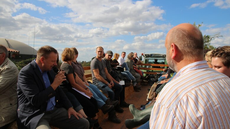 Mehrere Personen sitzen in einem Hänger, der von einem Traktor gezogen wird.